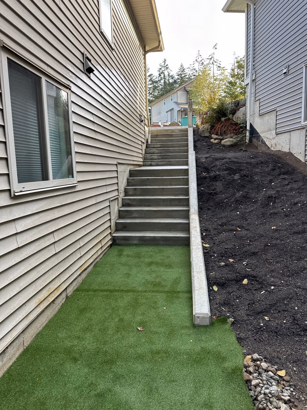 Concrete steps alongside a house with artificial turf