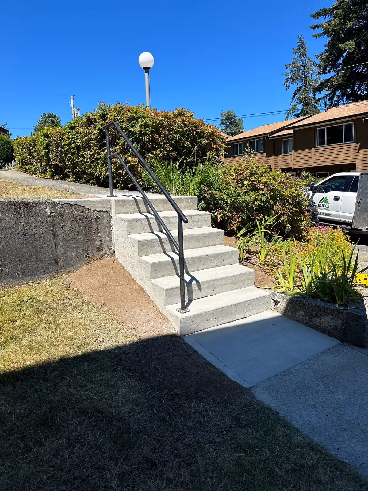 Concrete entry steps with a black metal railing