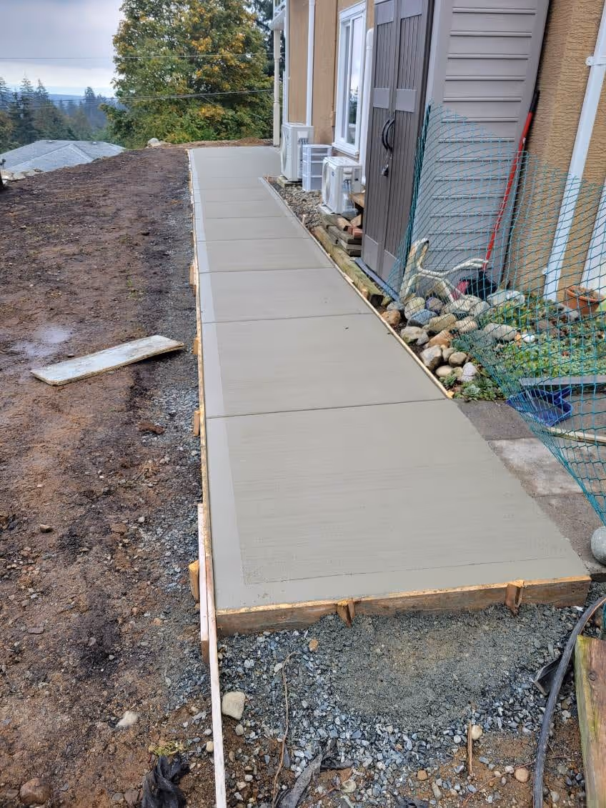 Fresh concrete walkway pour alongside a house