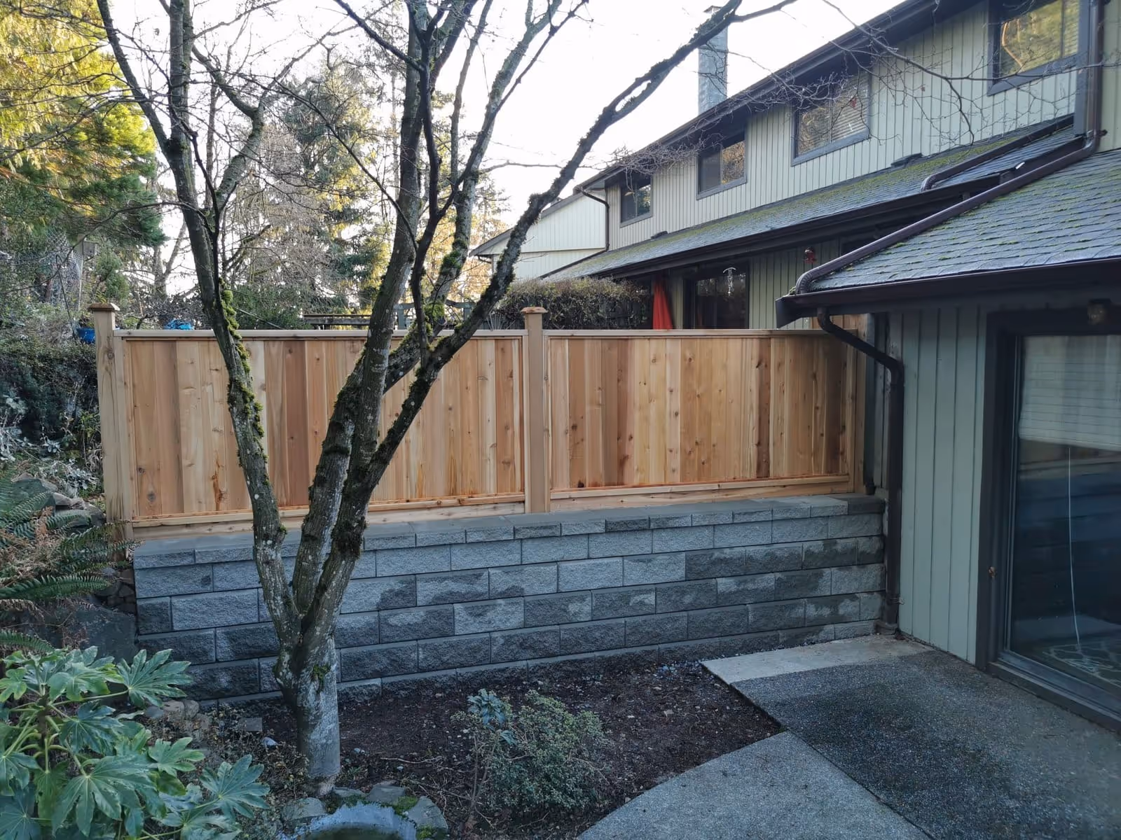 Cedar fence atop a stone block retaining wall