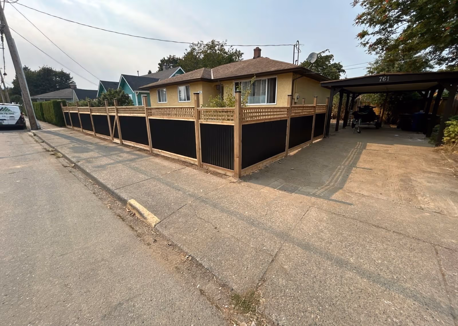 Wood frame fence with black metal panels, street side