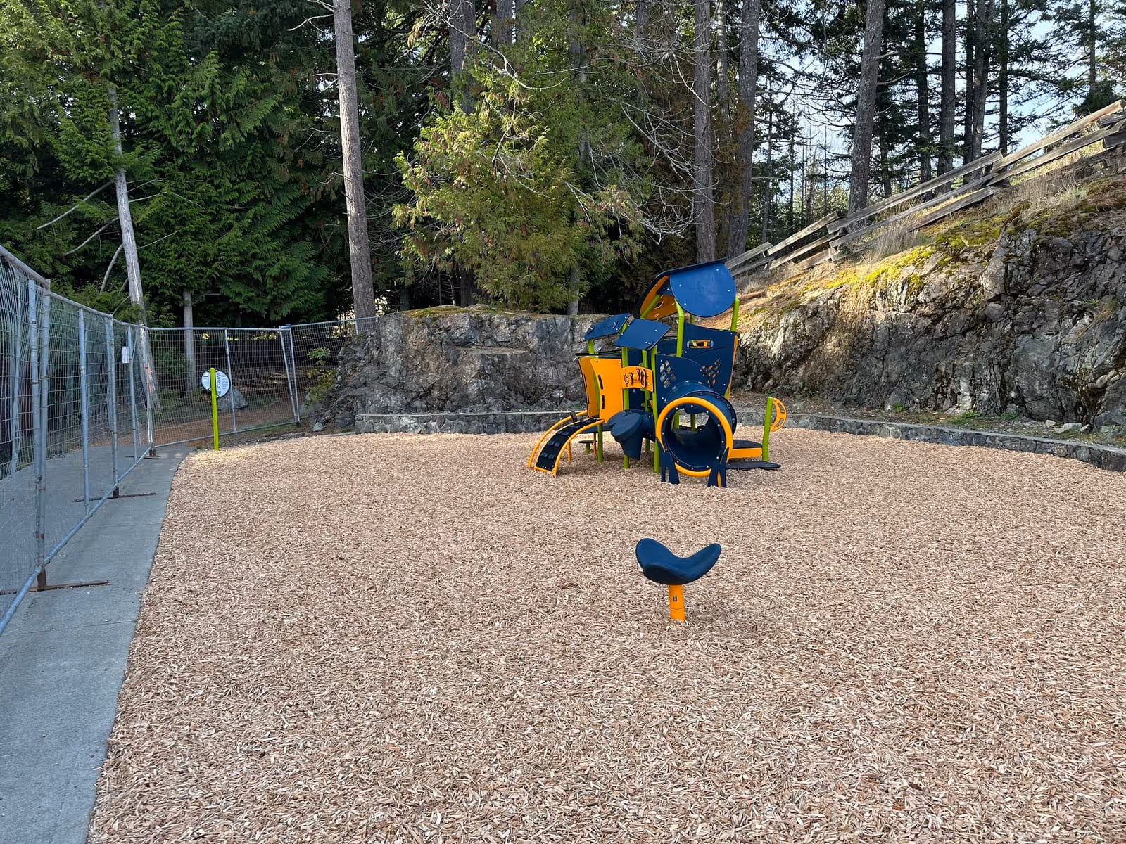 Playground with blue and yellow equipment and wood chip surfacing