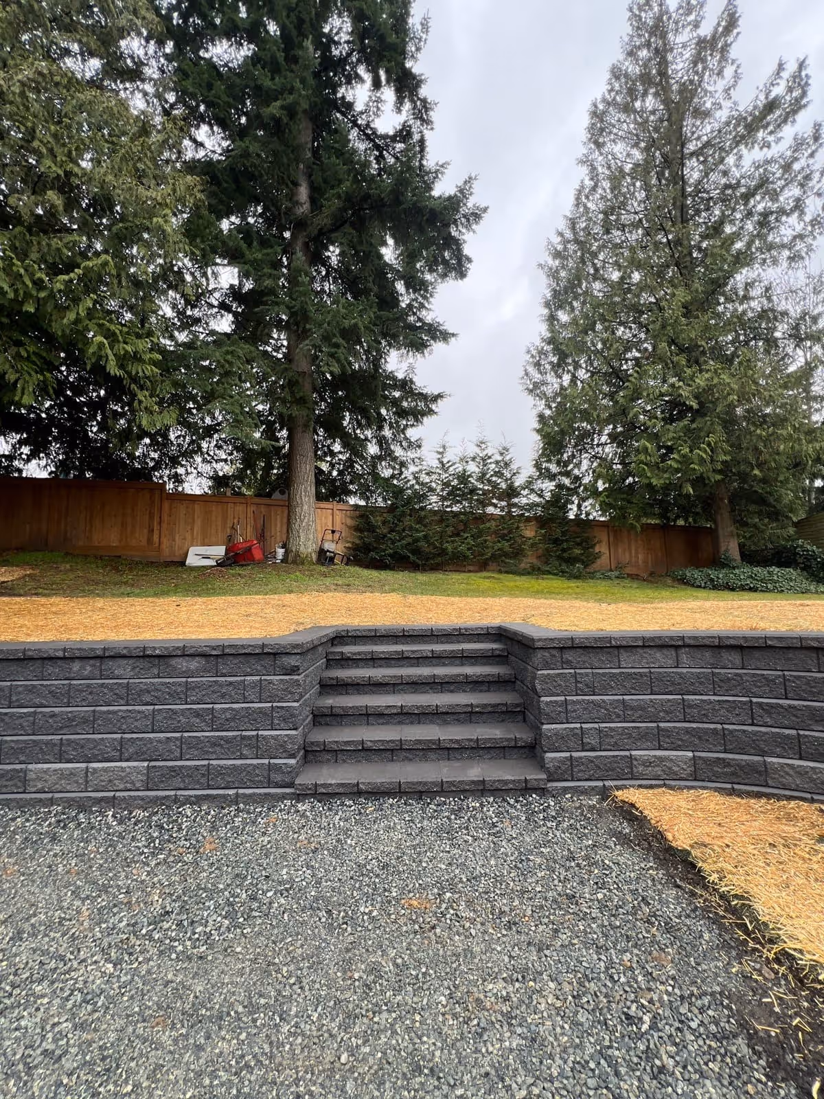 Dark charcoal block retaining wall with steps and gravel