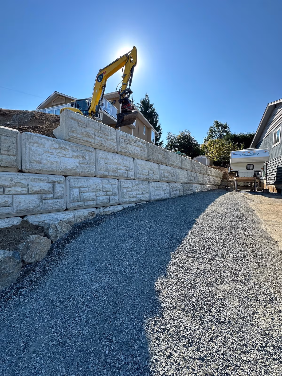 Excavator building a large concrete block retaining wall