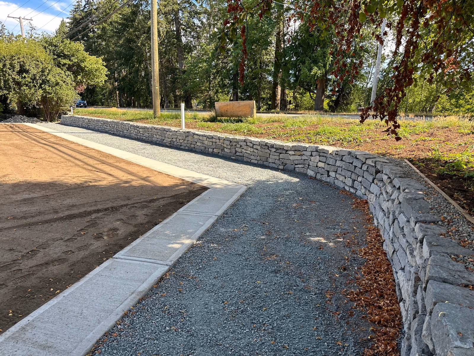 Granite block retaining wall with a gravel driveway
