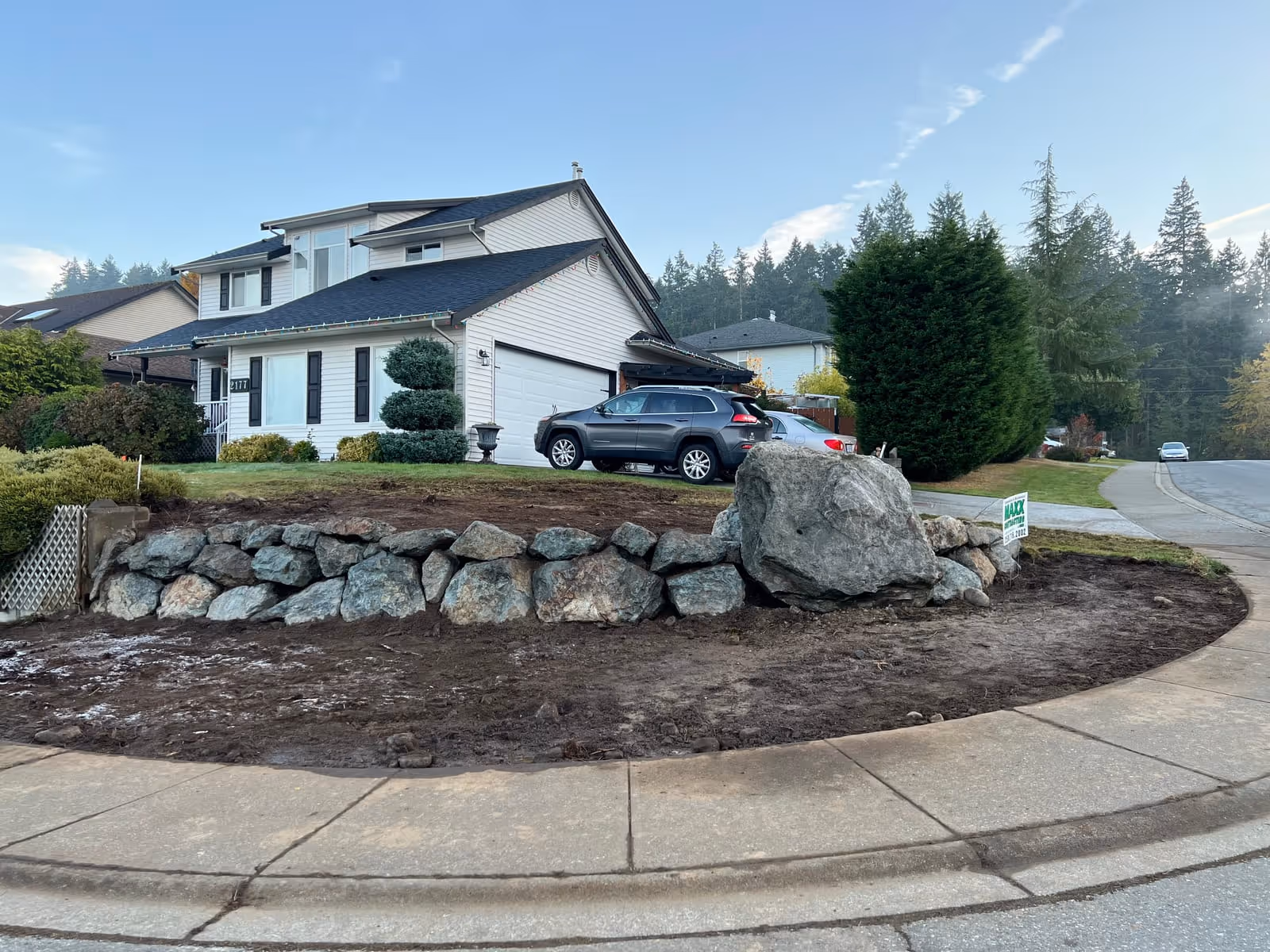 Natural boulder retaining wall with a rock feature in a front yard