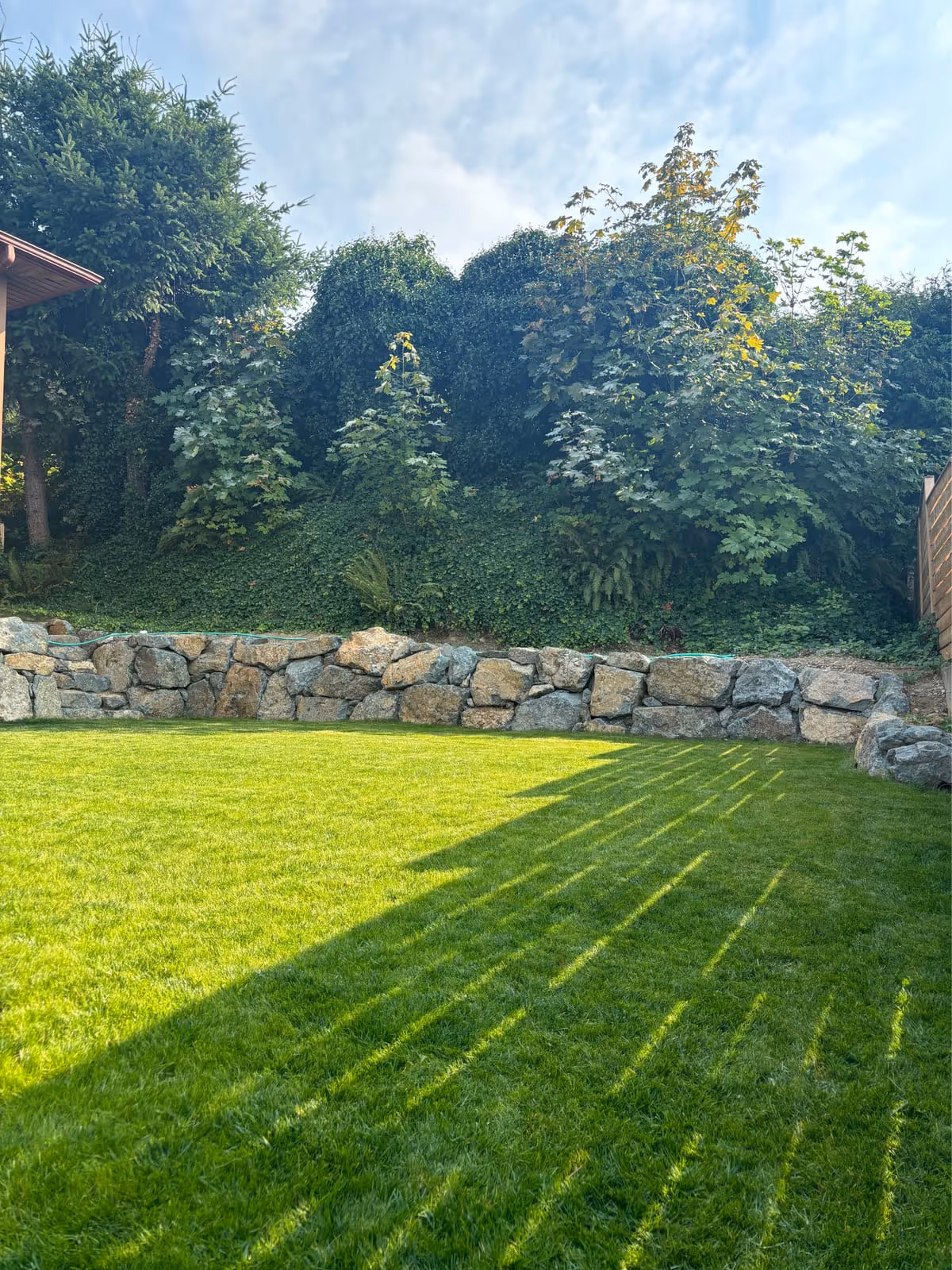 Natural stone retaining wall with a backyard lawn